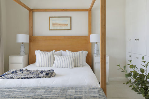 Light bedroom with wooden four-poster bed and nightstands