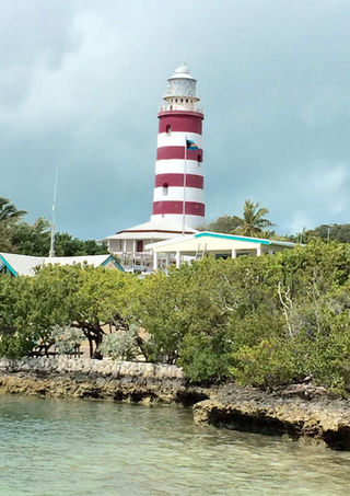 Red and white striped lighthouse in front of the ocean.