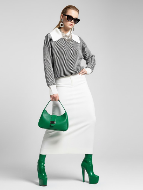 Fashion model in grey sweater, white skirt, vibrant green accessories.