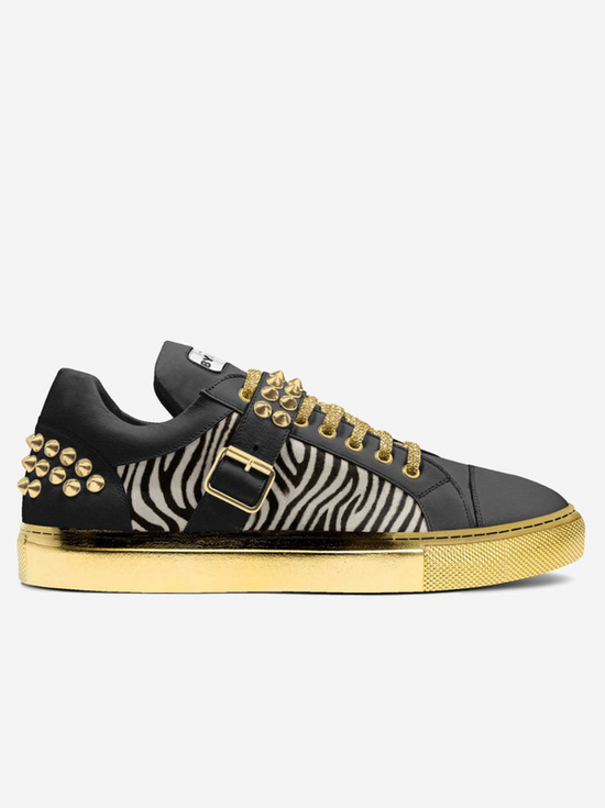 Black leather sneaker with zebra print, gold studs, laces, and sole.