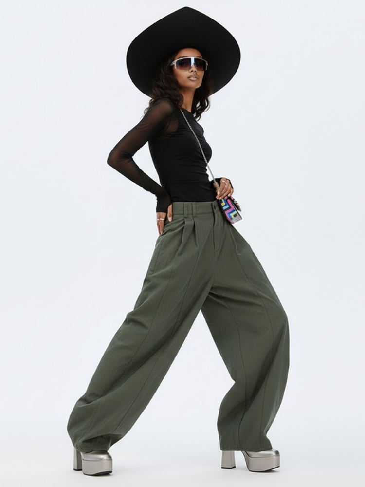 Miniatura: Stylish woman wearing black sheer top, olive wide-leg pants, hat, sunglasses.