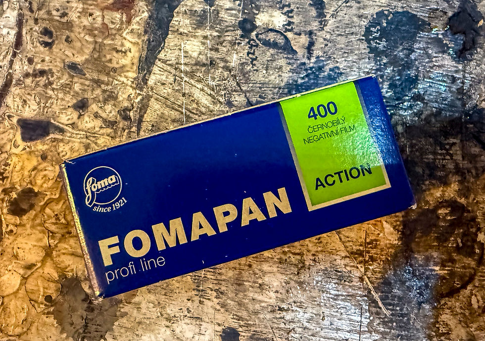 FOMAPAN 400 film box lies on a textured surface. Blue box with green label, text reads "ACTION" and "Since 1921." Vintage feel.