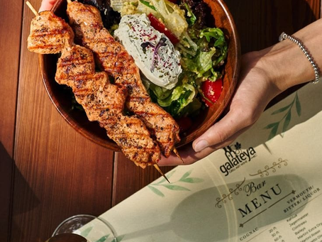 A bowl of colourful vegetables and grilled meat with a spoon of greek yogurt