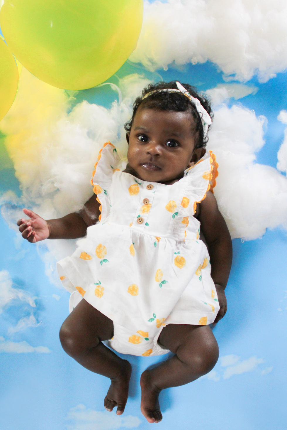 Baby on clouds holding a balloon.