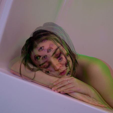 A woman lays with her eyes closed with multiple images of eyes on her face.