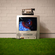 A still from a video of a CRT monitor featuring a clown woman getting ready.