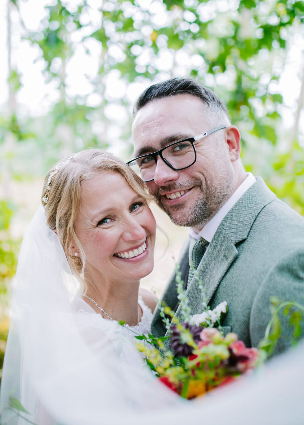 a bride and groom are posing for a picture and the bride is wearing glasses