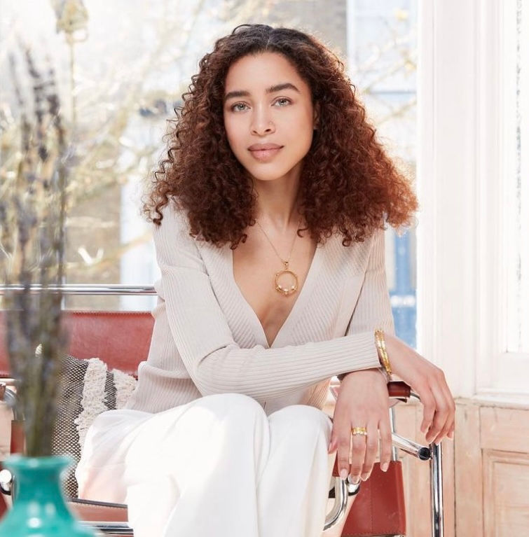 a woman wearing a necklace and bracelet is sitting in a chair