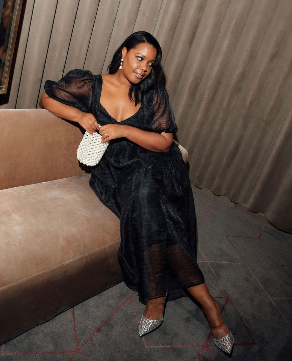 a woman in a black dress is sitting on a couch