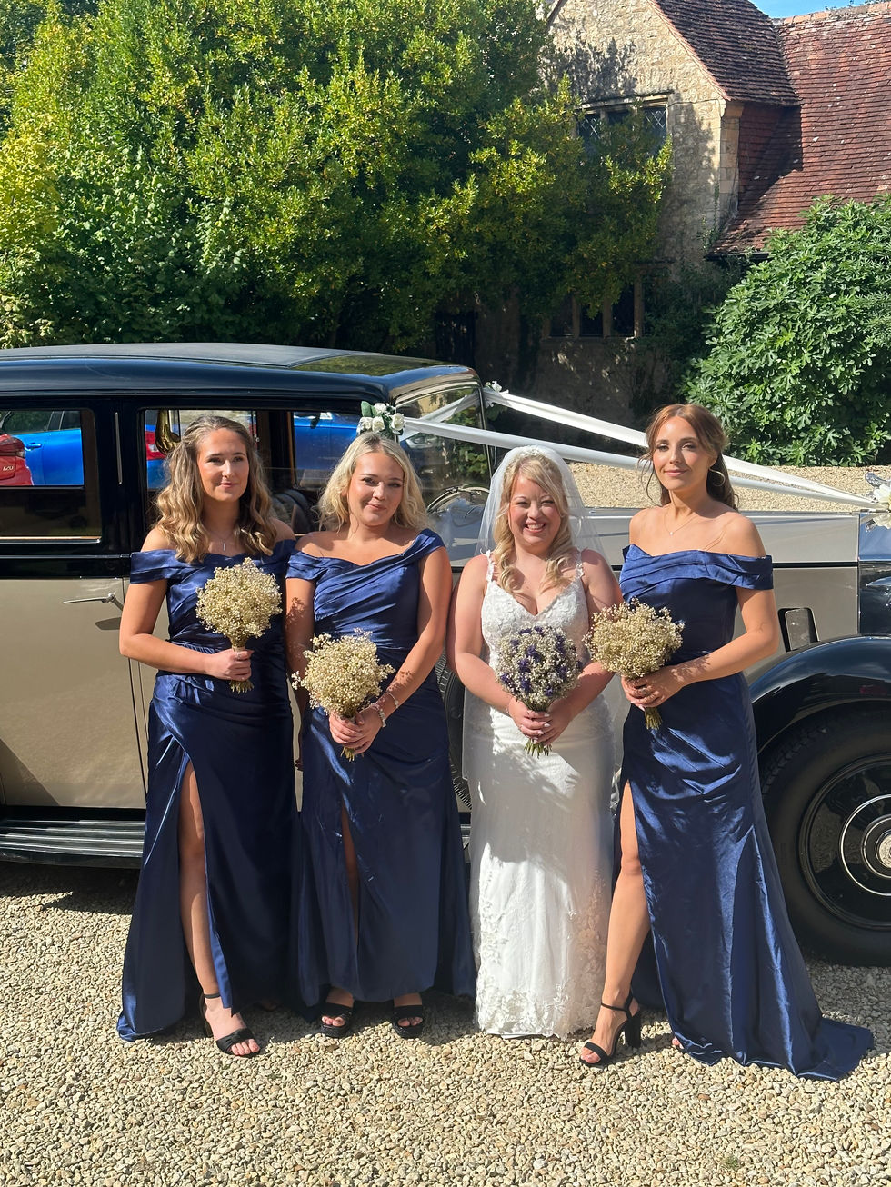 a bride and her bridesmaids pose in front of a car