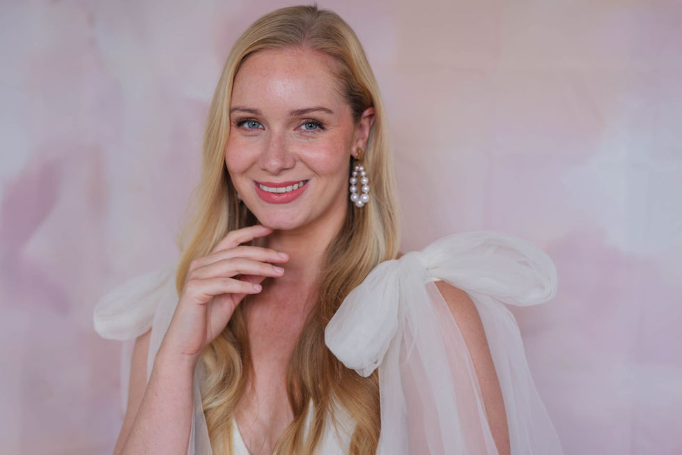 a woman wearing a white dress and pearl earrings smiles for the camera