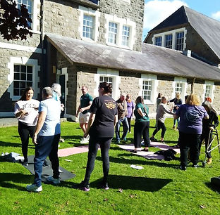 Group of people outside together in the sunshine on a grassy area doing casual self-defense
