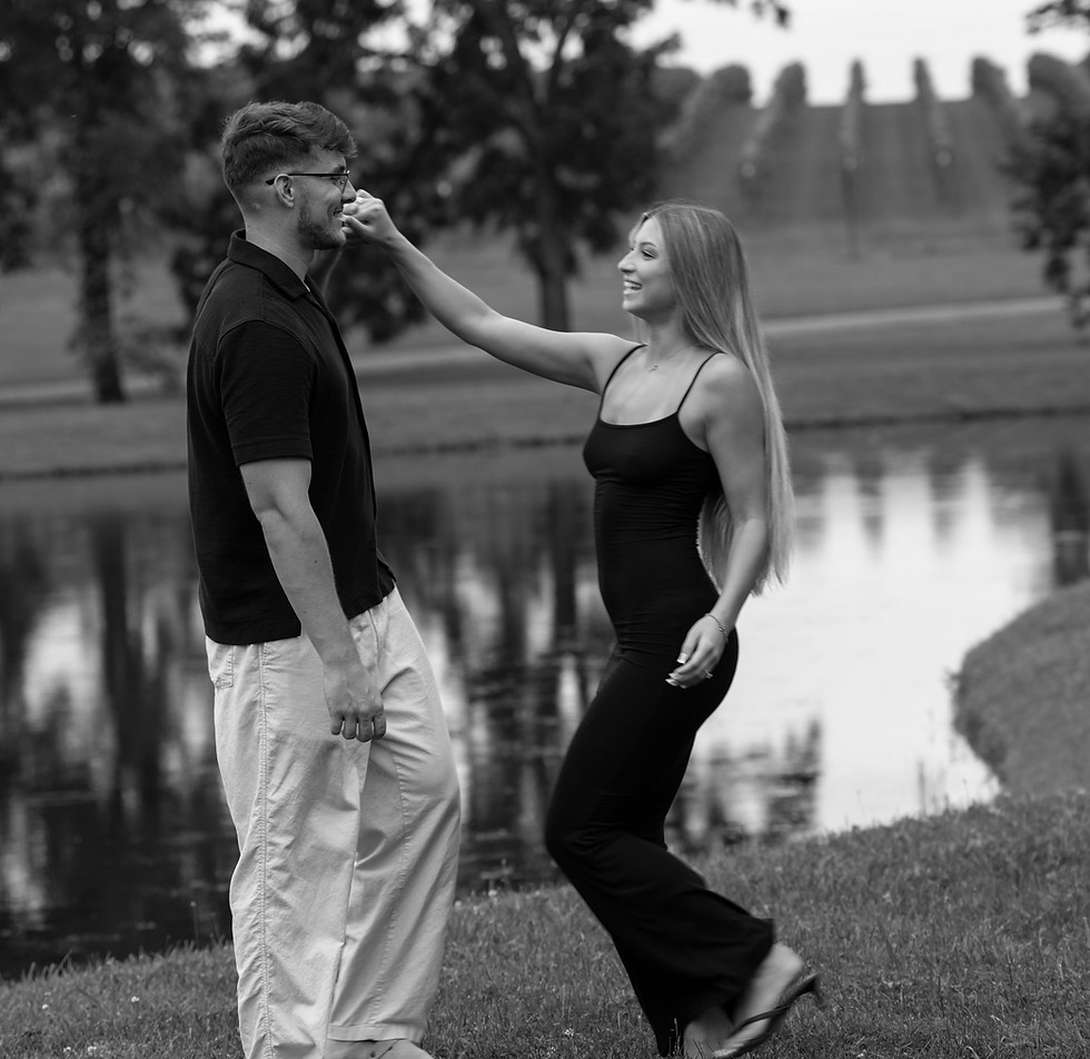 Black and white portrait of a couple standing together by the water at dusk