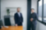 Two diverse men in business suits stand in a modern office.