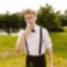 Gus from Aha Sugar Co posing playfully outdoors in suspenders and bow tie uniform for dessert cart events.