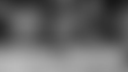 Runners in motion, captured in blurred black and white. Legs are mid-stride. A crowd watches in the park. Athlete numbers barely visible.