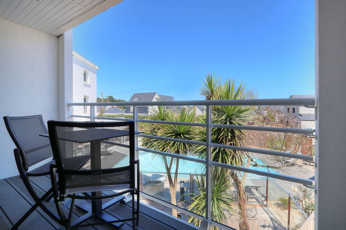 Balcon avec vue sur la piscine et palmiers depuis la Chambre Confort à l’Hôtel Le Bellevue à Quiberon