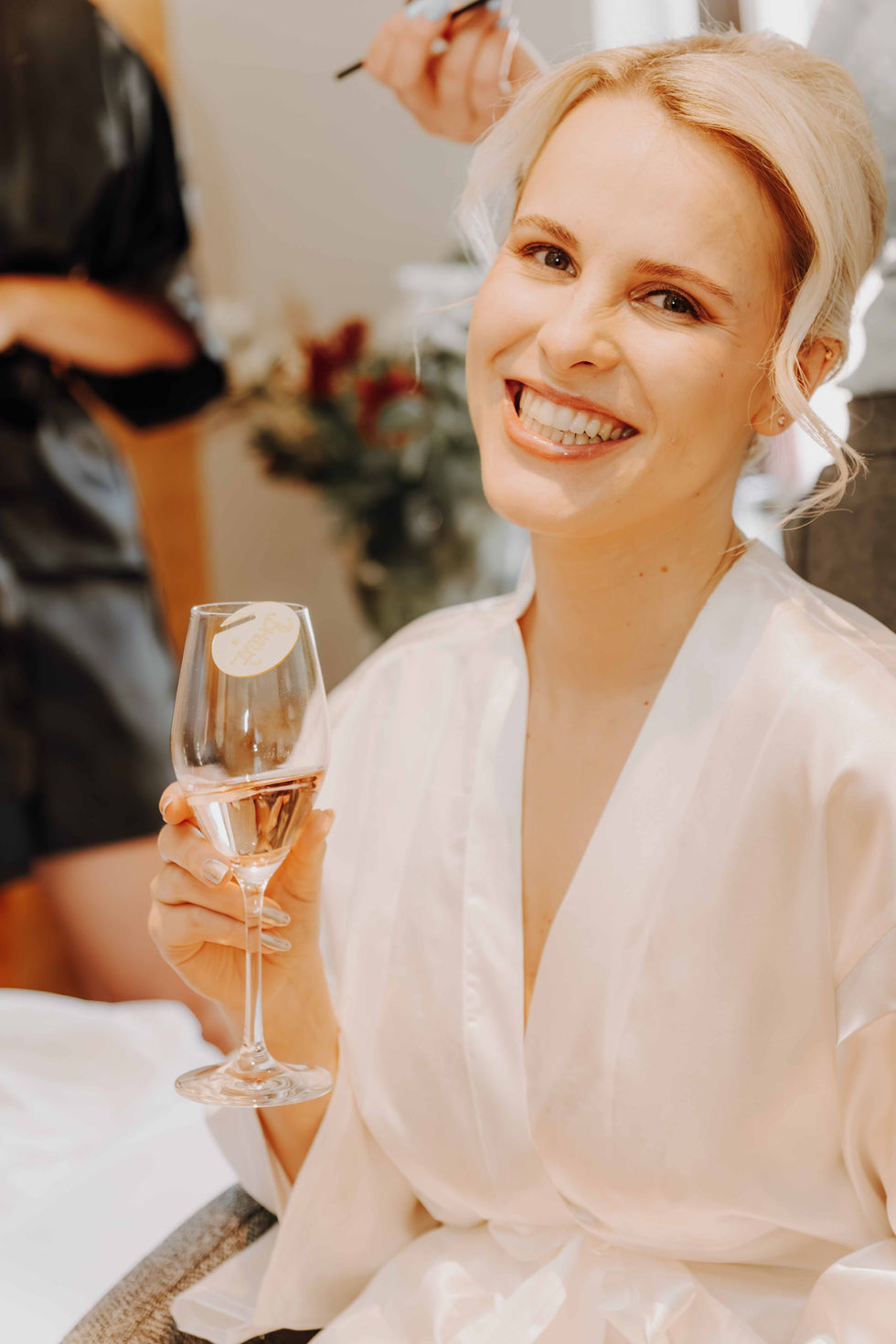 Haare werden gestylt, Braut mit Glas Sekt