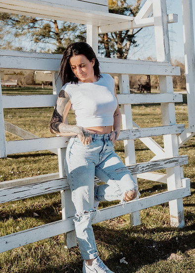 Portraitaufnahme am Heidesee, Person in Jeans und weißem Oberteil, angelehnt an einen Hochstuhl, natürliche und entspannte Fo