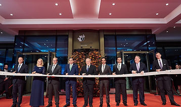 Gruppe von Personen schneidet weißes Band bei feierlicher Eröffnung.