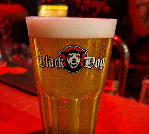 A glass of pilsner with Le Black Dog logo on it