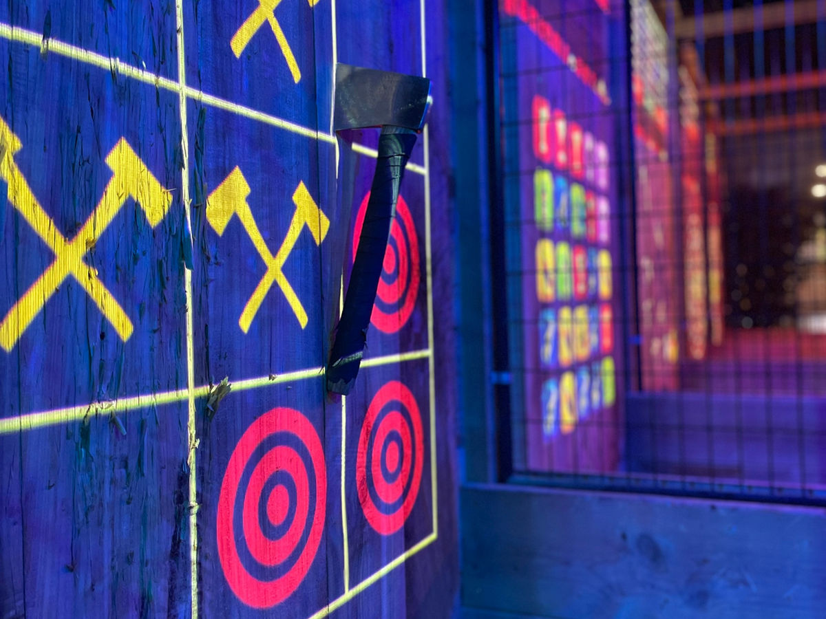 Axe stuck in a wooden target with glowing digital projections at Madison Axe on Madison's east side