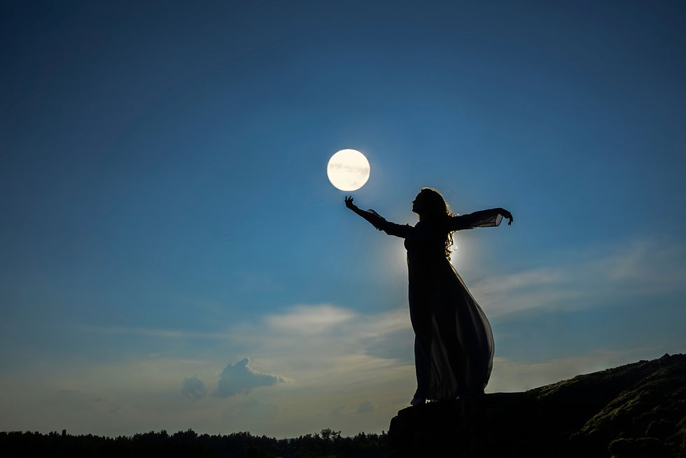 Silhouette of a woman standing on top of a mountain. A female holds in her hand a full moon above the forest trees. Backlight and moonlight. Full moon in Capricorn 2025.