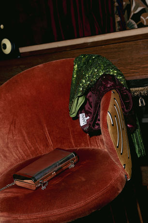 Green sequin party piece and clutch on a red velvet chair, fashion rental at RENTGLAM in Amsterdam