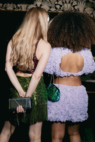 Back view of two women in a green sequin skirt and a lilac sequin open-back top, party outfits rented from RENTGLAM in Amsterdam