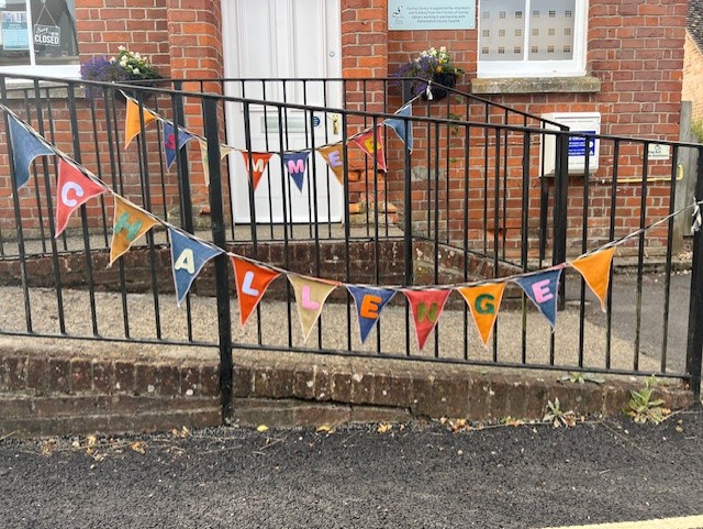 Colourful handmade fabric bunting reading SUMMER READING CHALLENGE displayed on handrail outside The Library
