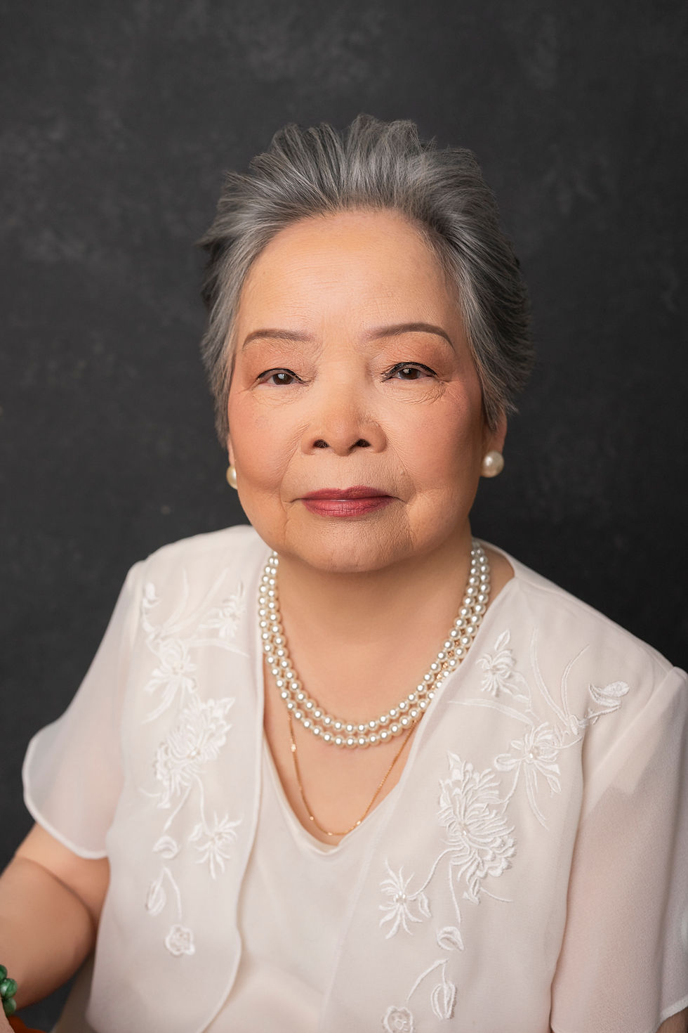 Older woman in pink dress poses for Professional family legacy video interview setup with lights and camera in Tacoma studio