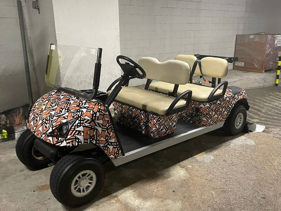 Six-seater golf cart with custom orange and black graphics
