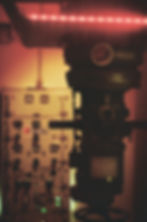 Silhouetted submarine periscope with control panel in dim, reddish light. "Périscope" text visible. Moody, vintage ambiance.
