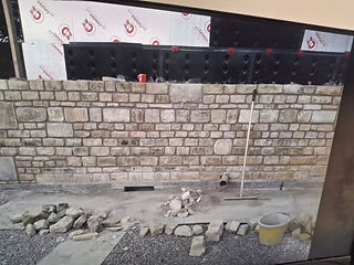 A partially constructed stone wall with insulation panels