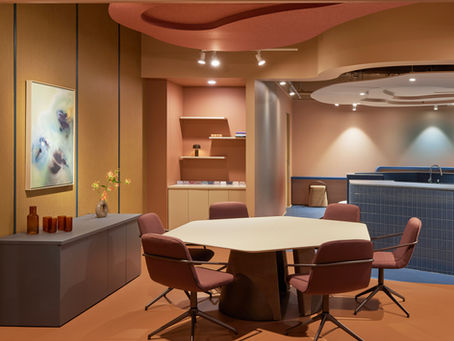 Modern meeting room with octagonal table, red chairs, abstract art, and warm beige walls. Soft lighting creates a calm, inviting ambiance.