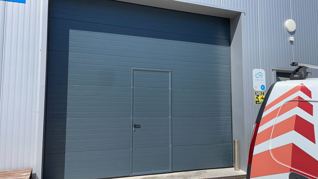 Instalação de portão seccionado industrial com porta de serviço em Surfcloud