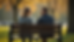 Eye-level view of two friends sitting on a park bench sharing a heartfelt conversation