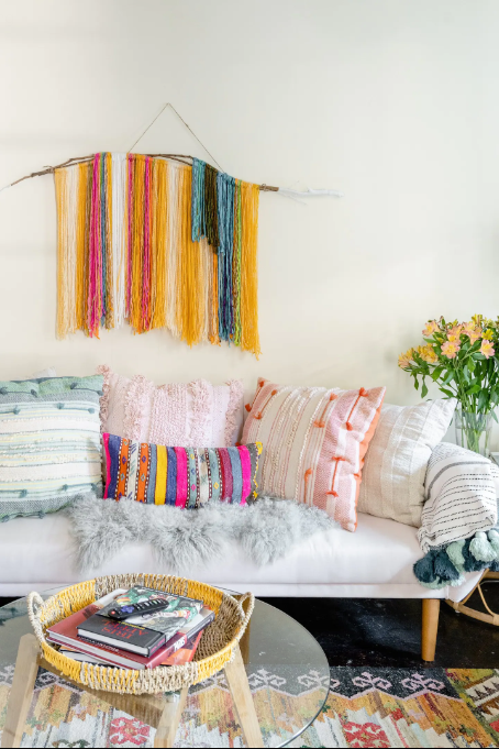 Soft, white sofa with colorful pillows, and colorful yard artwork inside the living area of The Guest House.