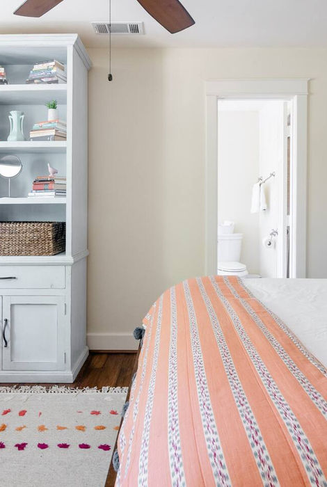 Tall white wooden bookcase in bedroom, filled with books.