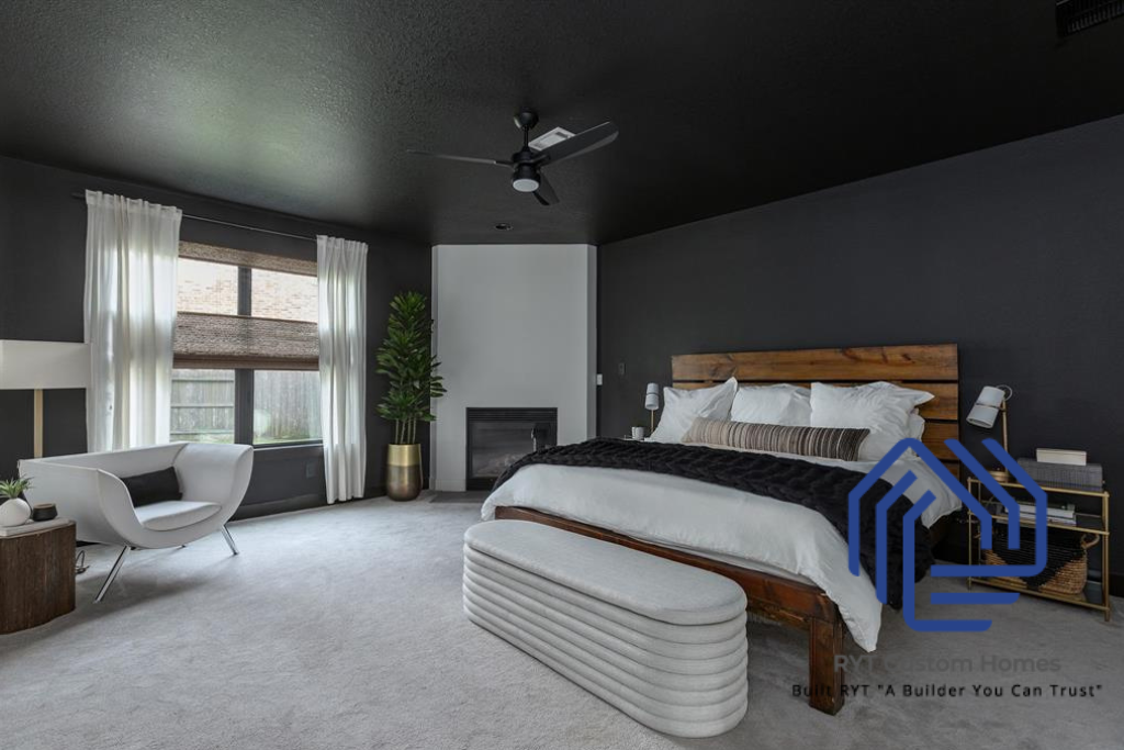 Primary bedroom with white carpet, black walls and a corner fireplace next to a large window. 