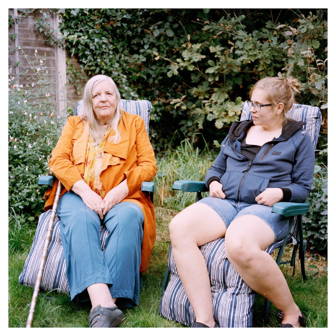Two women seated next to each other in lounge chairs with landscape in the background.
