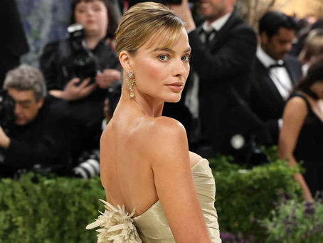 Margot Robbie shines in a soft metallic Chanel gown and breathtaking canary-yellow diamond earrings as she makes her appearance at the Met Gala.