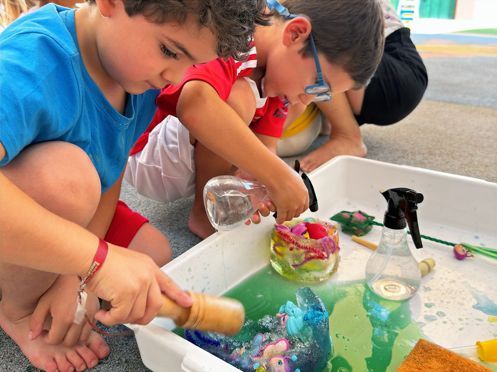 Crianças da Educação Pré-Escolar exploram peças de gelo durante uma atividade de psicomotricidade sensorial.