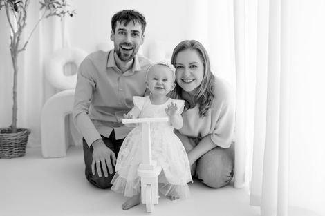 One-year-old baby sitting beside birthday cake in photography studio. | Einjähriges Baby sitzt neben einer Geburtstagstorte im Studio.