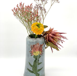 Blumenvase hellblau mit silisierter Blume in grün und rosa.