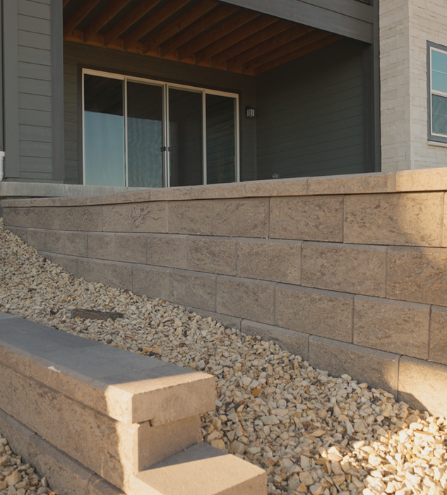 An allan block retaining wall that forms the foundation of a patio.