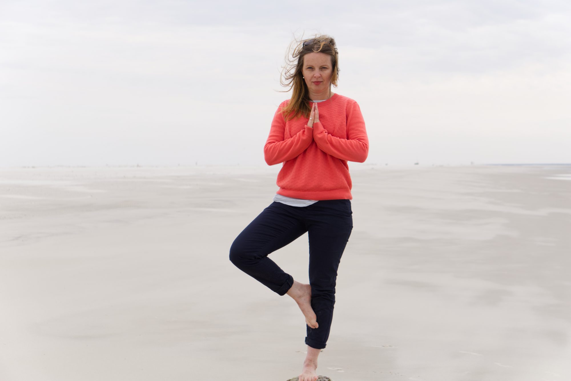 Frau steht auf einem Pfosten am Strand
