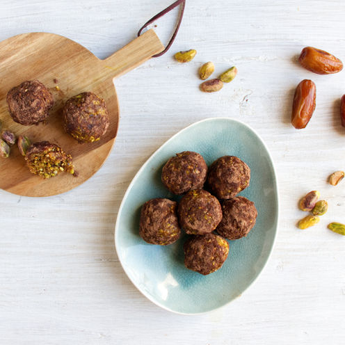 Energy Balls auf einem Brett und Teller liegend mit Datteln und Pistazienkerne