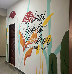 mural artístico baseado no salmo 100 pintado à mão com tons alegres como amarelo, verde água, vermelho e laranja na redepção lateral de uma igreja