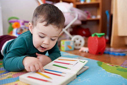 young toddler boy looking at books and playing in his room